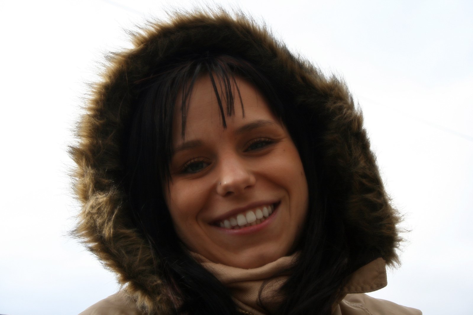 a woman smiling for the camera, with her hood pulled over