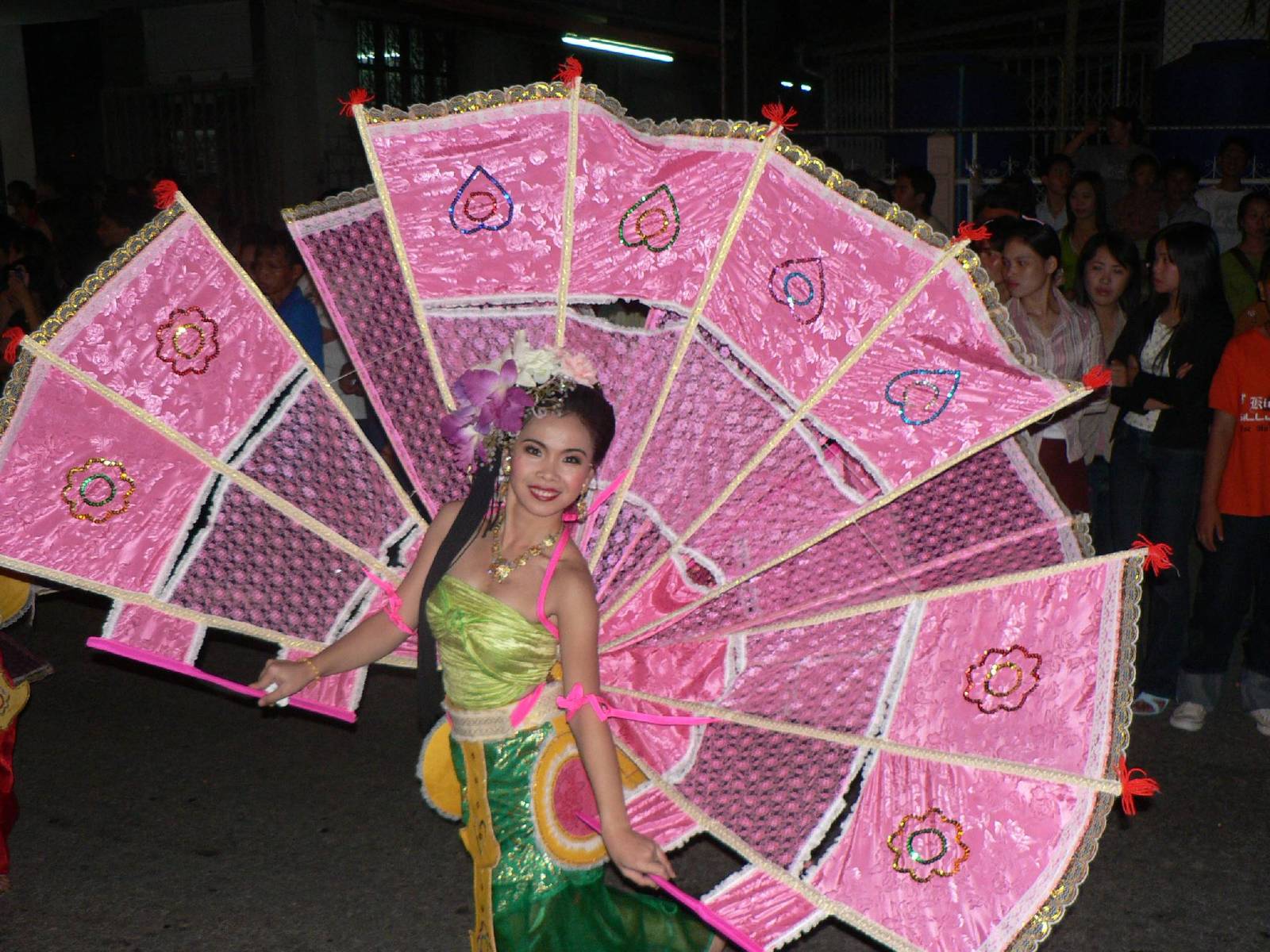 a woman in green holding pink and gold parasol