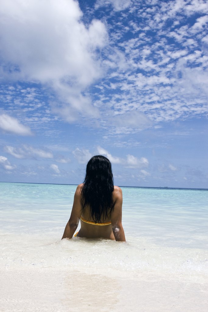 a woman in a yellow bikini looking at the ocean