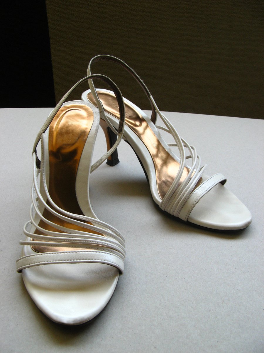 woman's white shoe with silver heels and straps