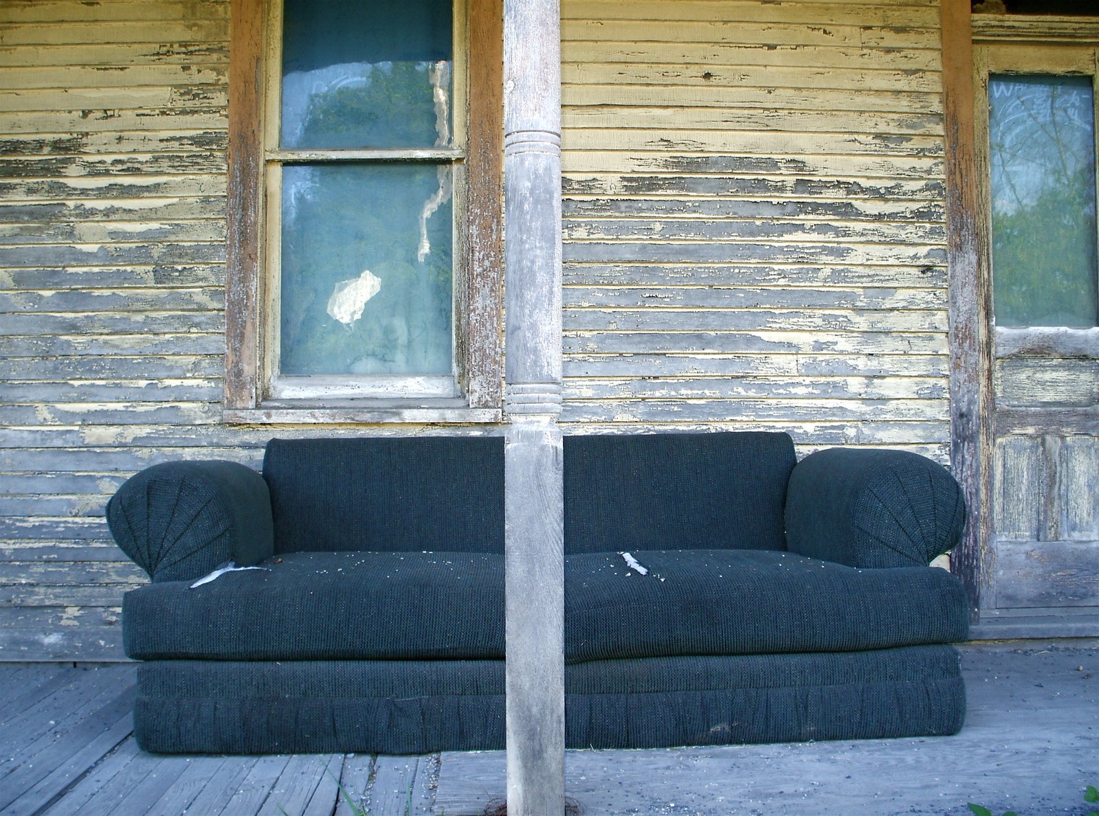 an old sofa sitting in front of a house