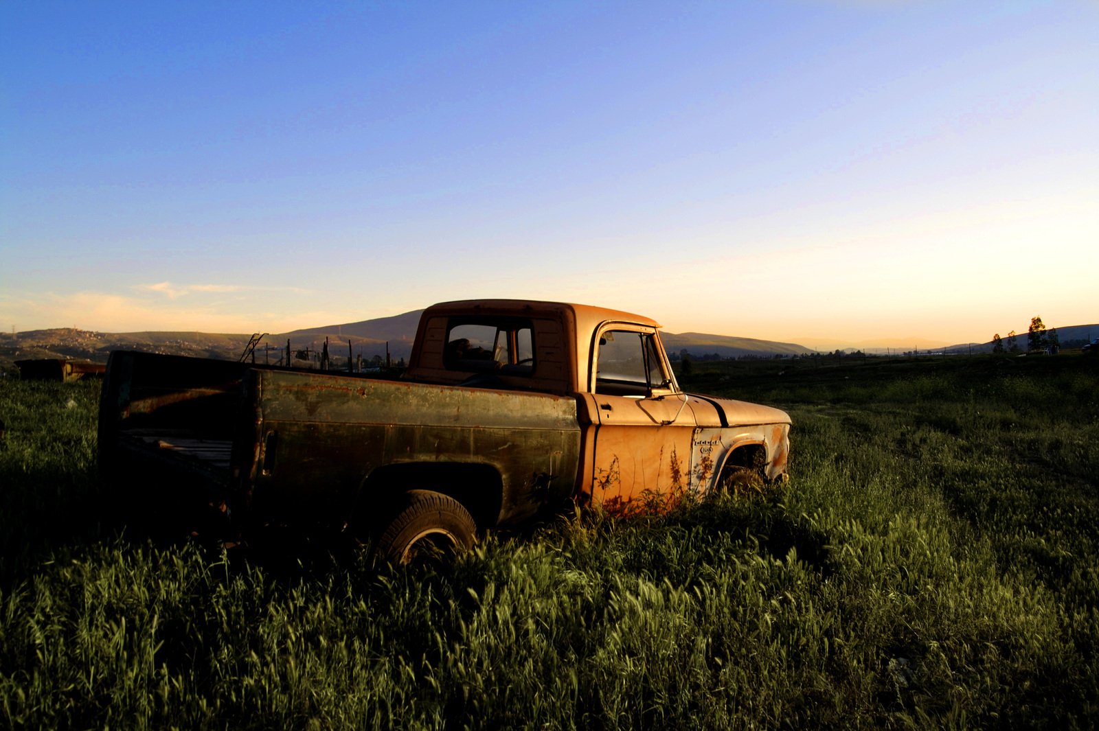 a old truck sits in the middle of a field