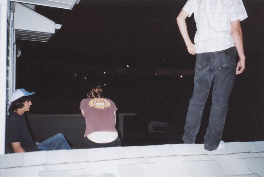 two young men sitting on a roof watching soing from below