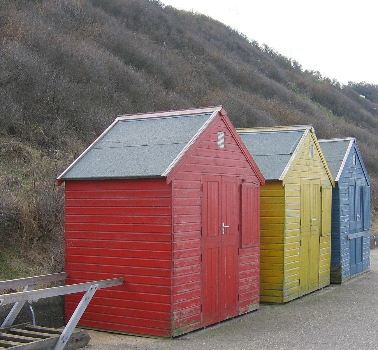 a group of colorful beach huts next to the side of a mountain