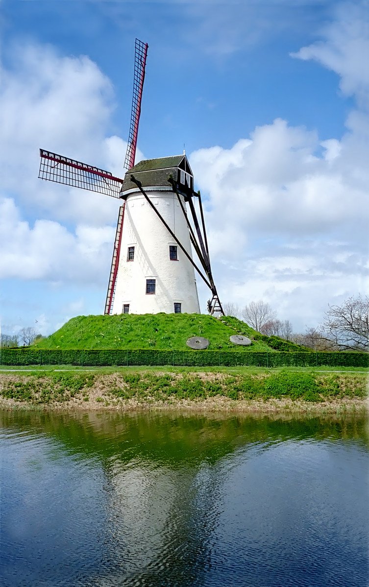 a windmill stands on top of a small mound