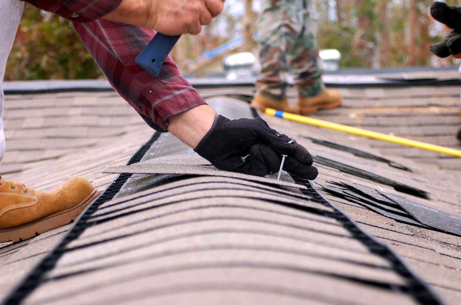 two men wearing gloves are on the roof repairing