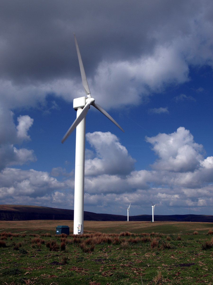 windmills stand in an open field against the cloudy sky