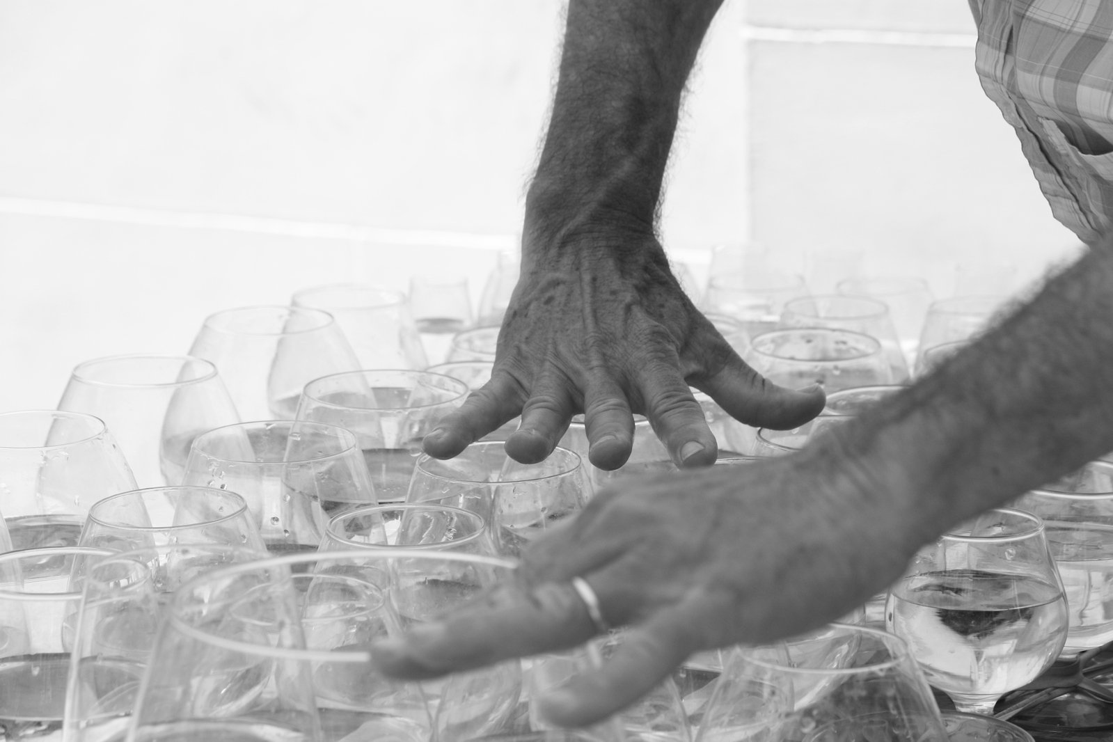 hands are reaching for wine glasses sitting on a table