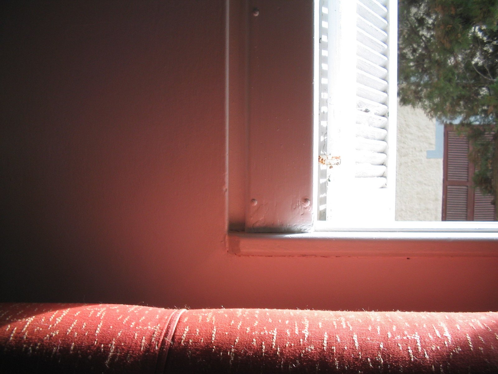 a red bench sits in a room with a window