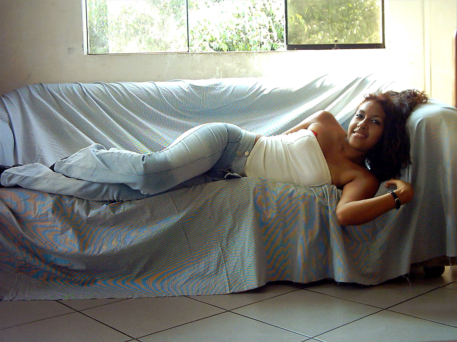 an attractive lady is laying on a couch covered by a sheet