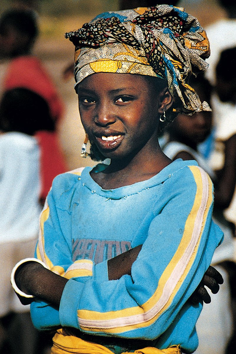 a girl with a scarf on her head smiles for the camera