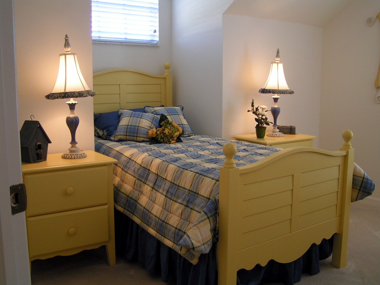 a room with a yellow dresser and small bed
