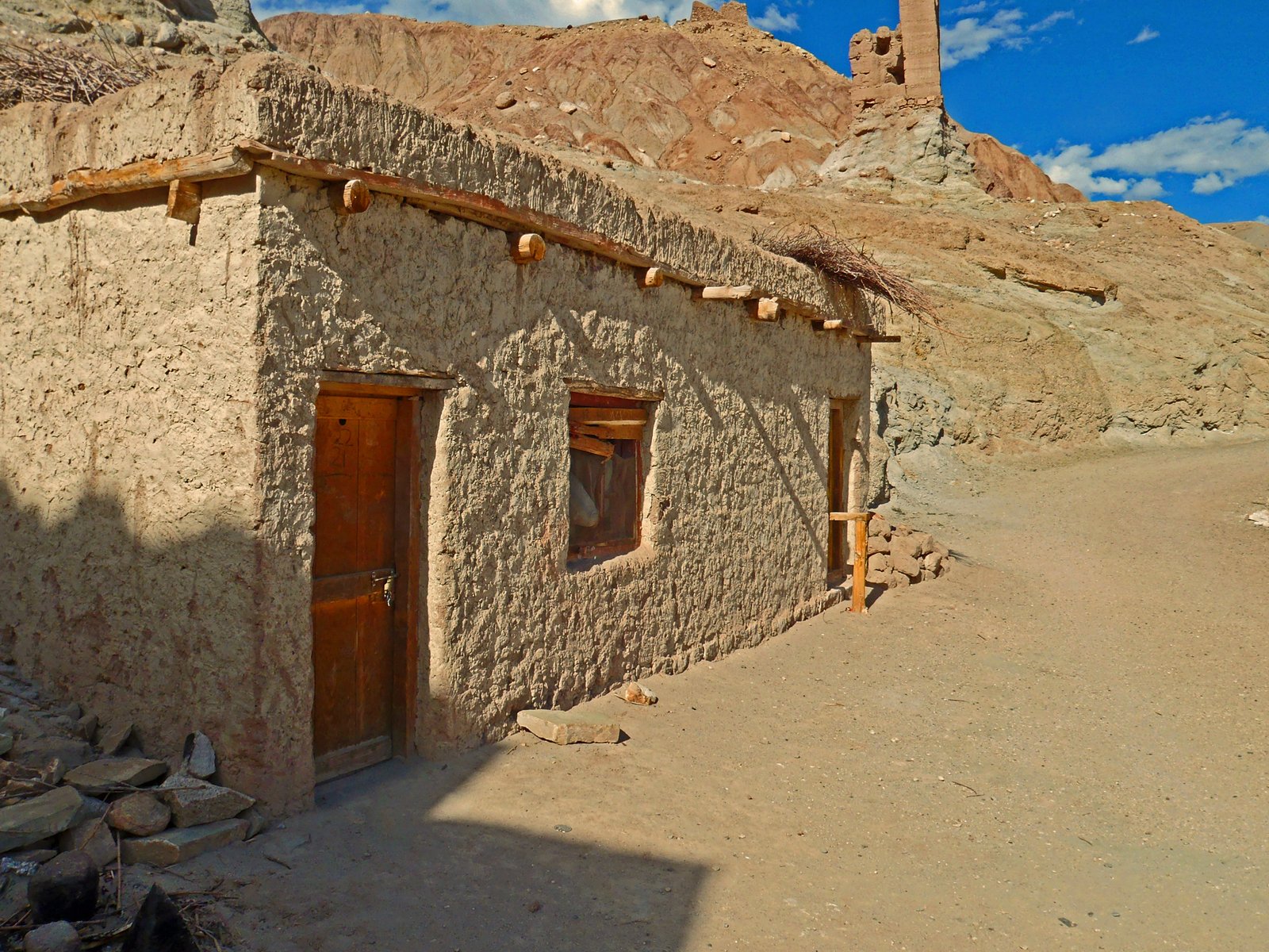 a stone house in the middle of a dirt field