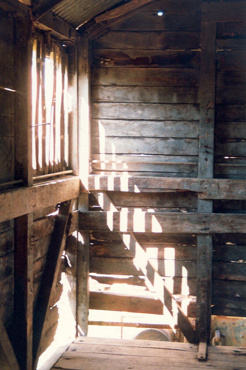 a wooden stairway with two handrails and a light from the window
