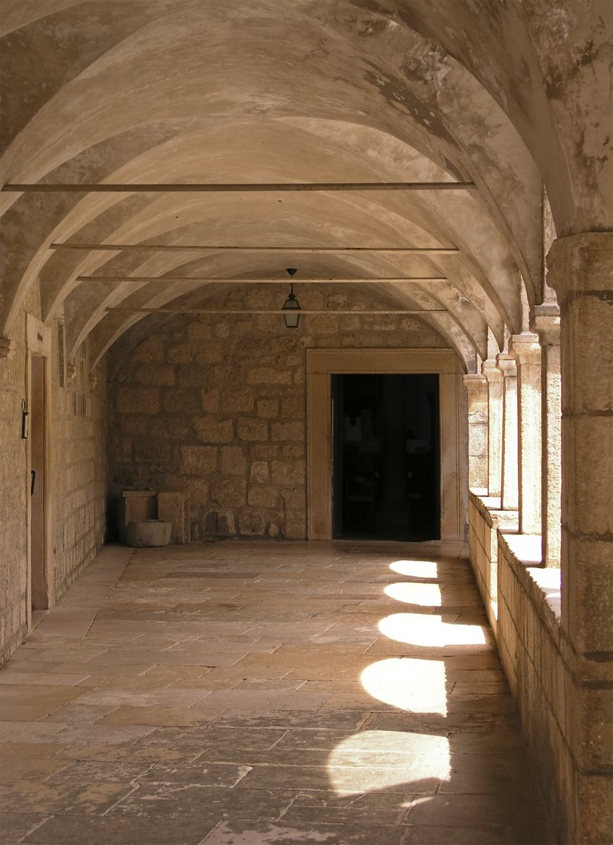 a very long stone hallway with many arches