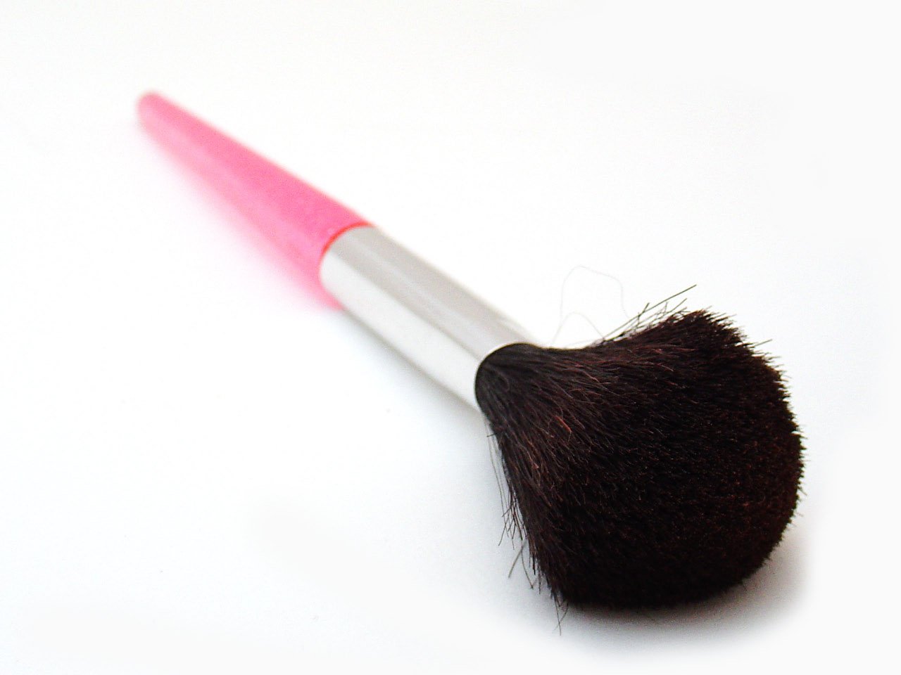 a pink makeup brush laying on its side