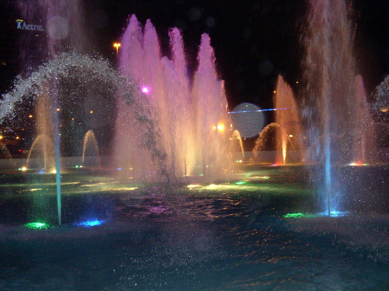 a large park with water fountains and lights at night