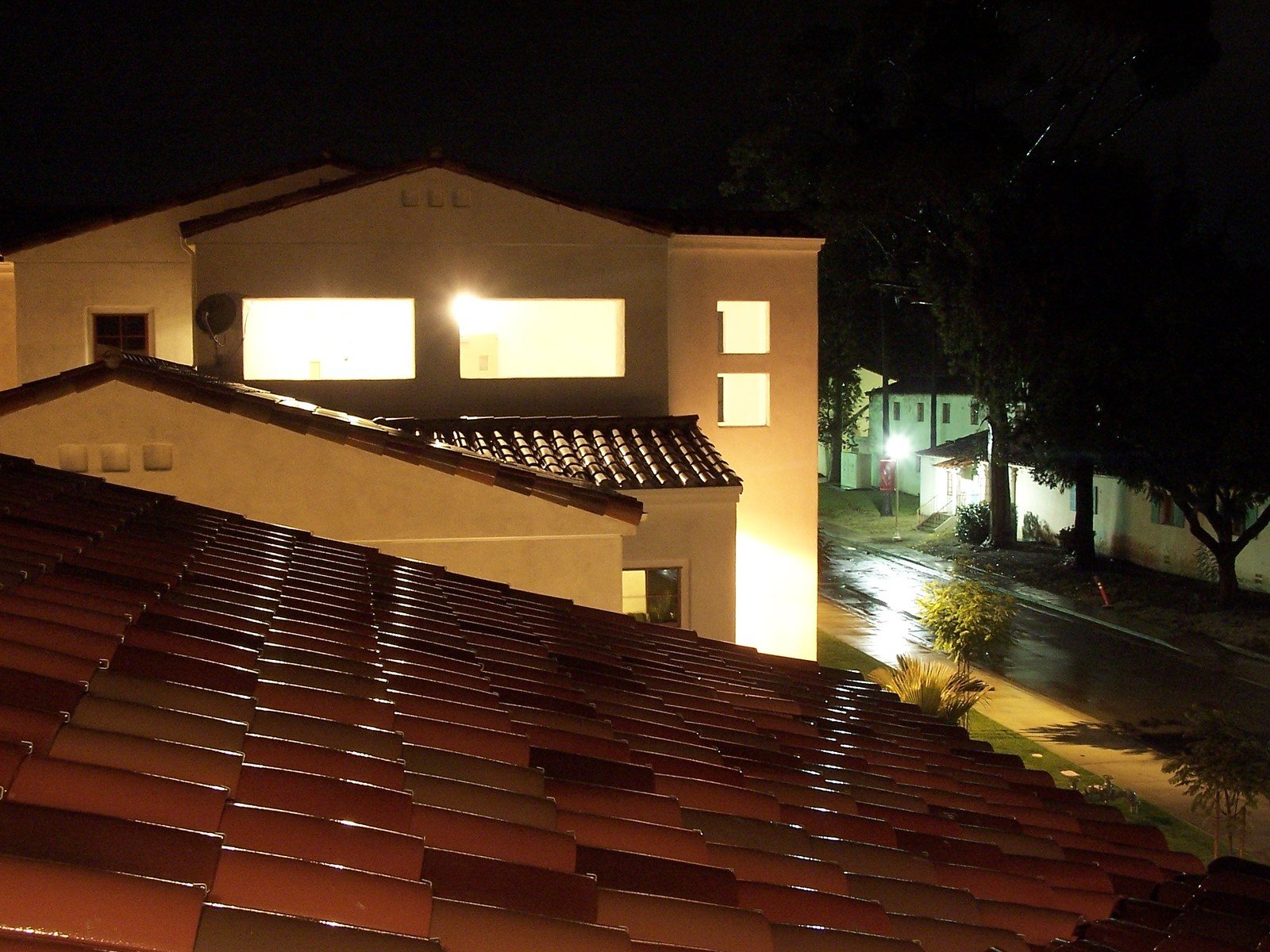 a view of a roof at night and the street behind it