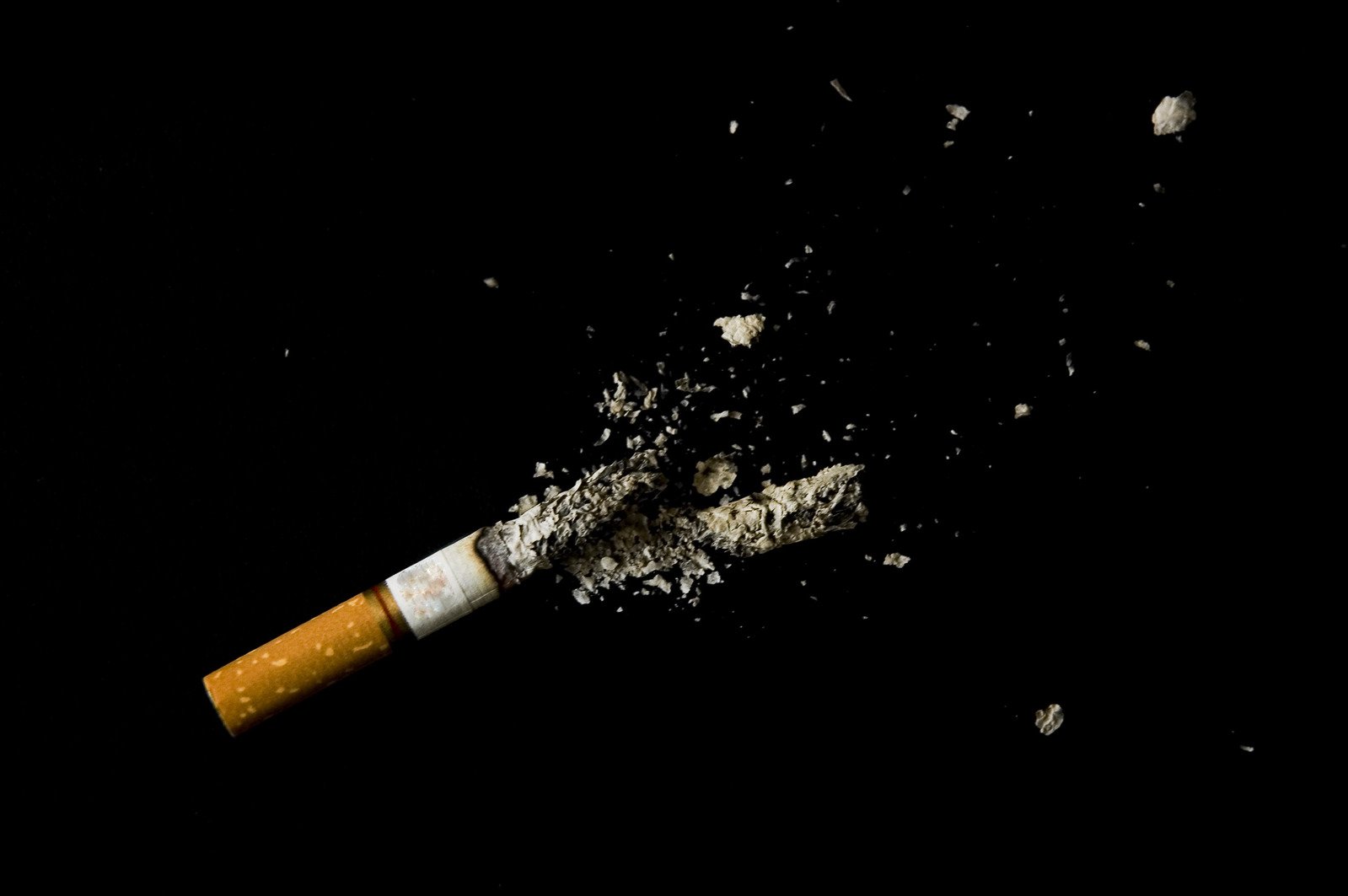 an opened cigarette is partially consumed and spilling in the air