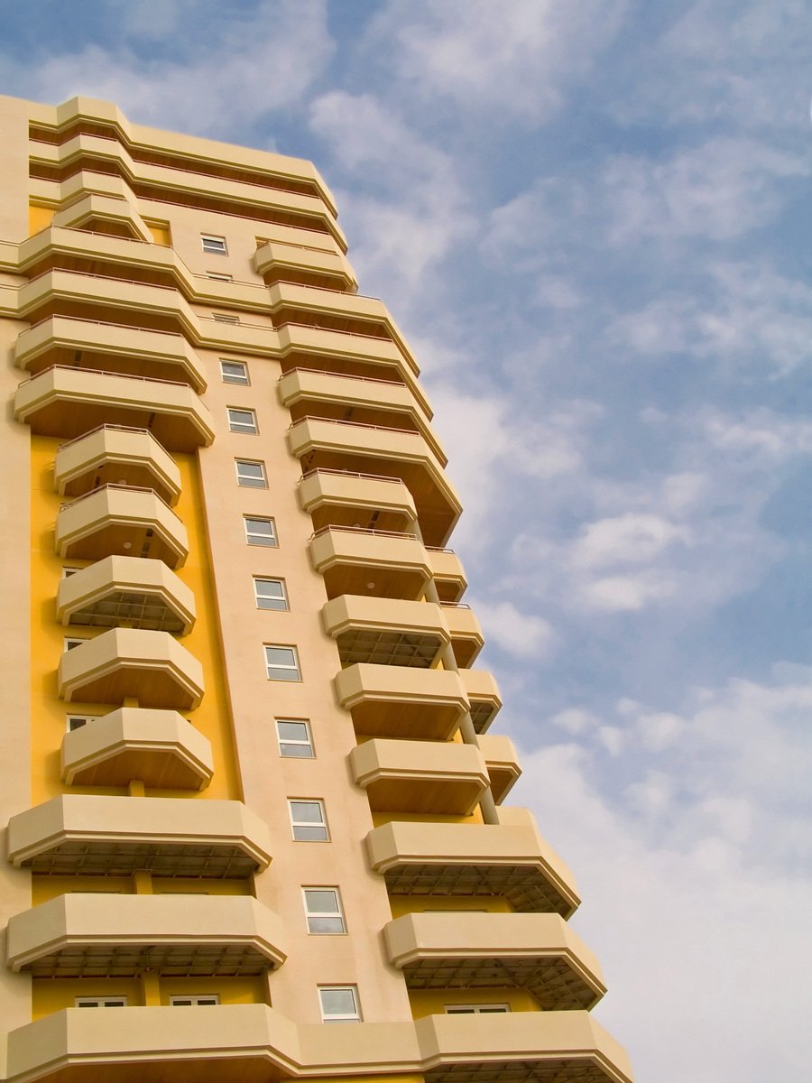 a tall yellow building is against the blue sky