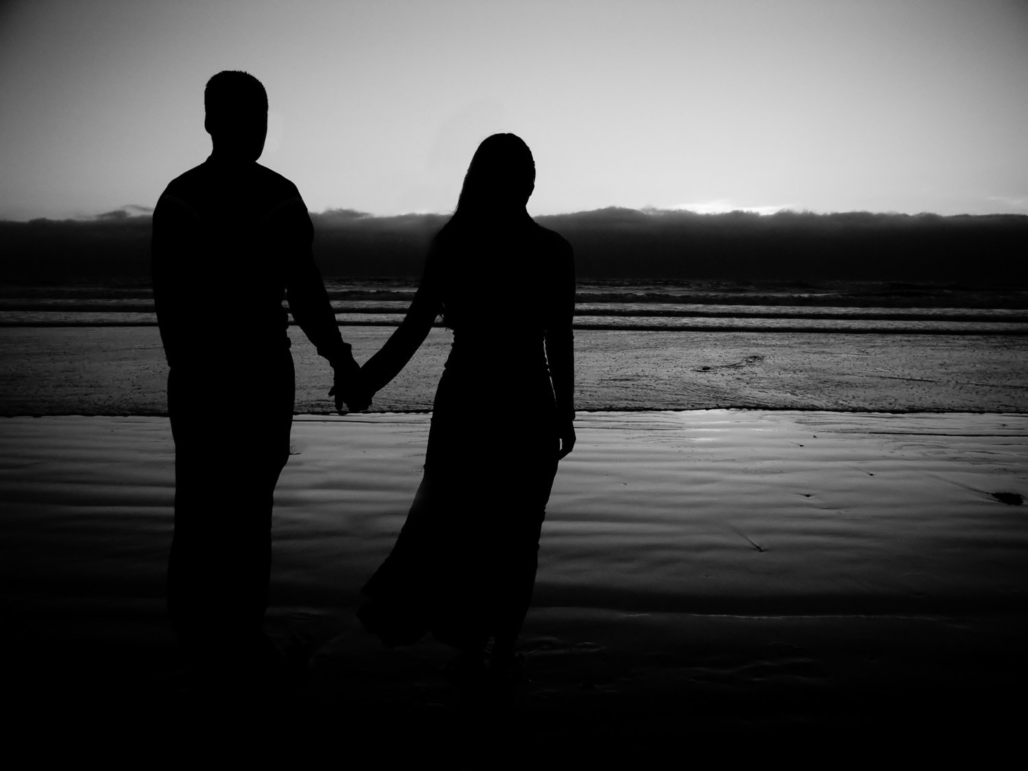 two people hold hands and stand near the water