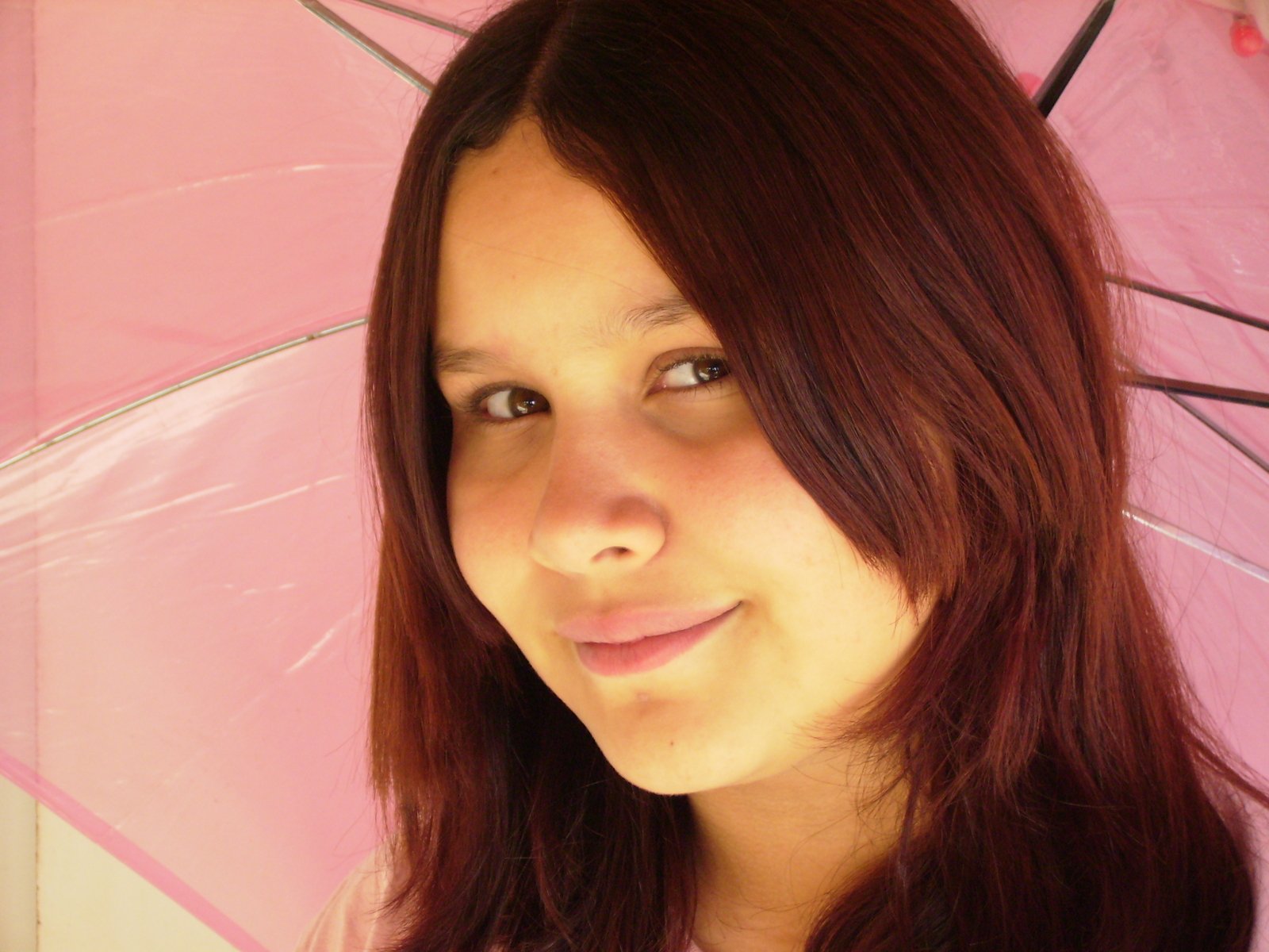 a woman is looking to her left with a pink umbrella