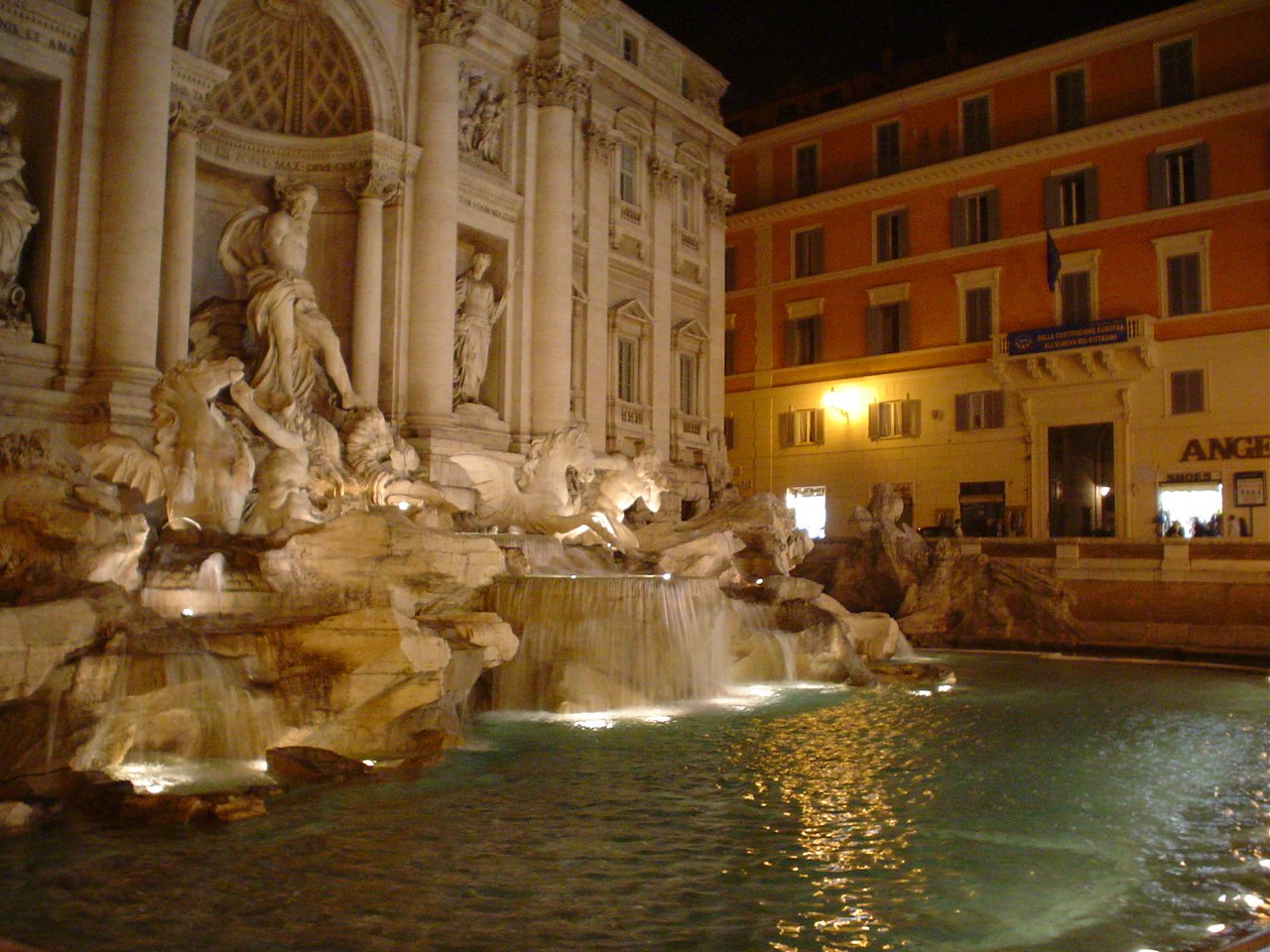 there are many statues surrounding the fountain in the night