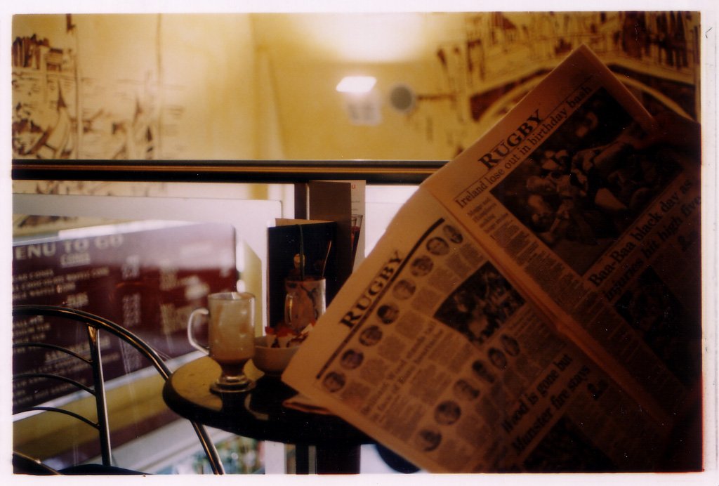 newspaper, glass, candle and small table near a window