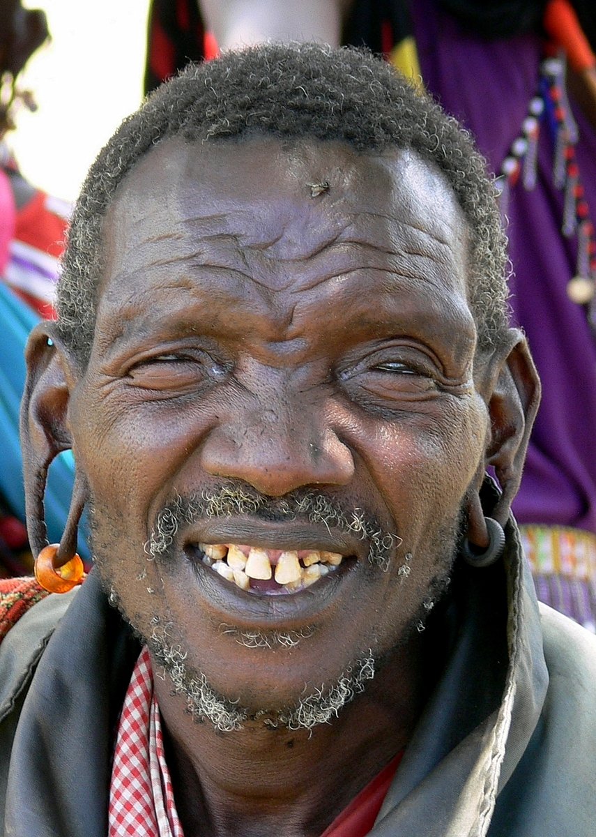 a man with dreadlocks and a smile is looking to his left