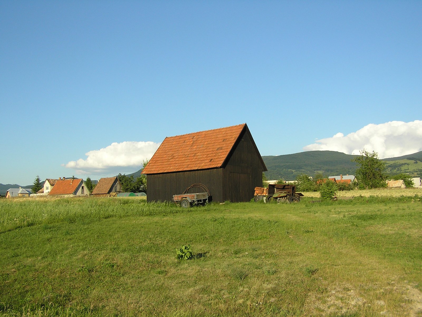 an old farm building sitting on top of a lush green field