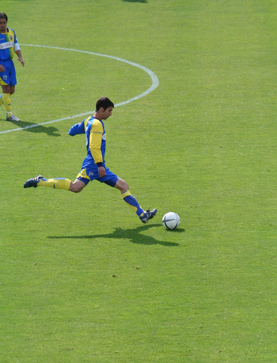 two soccer players kicking a soccer ball on the field