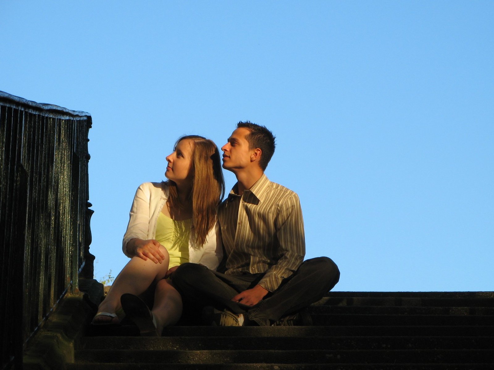 a man and woman sitting on steps at sunset