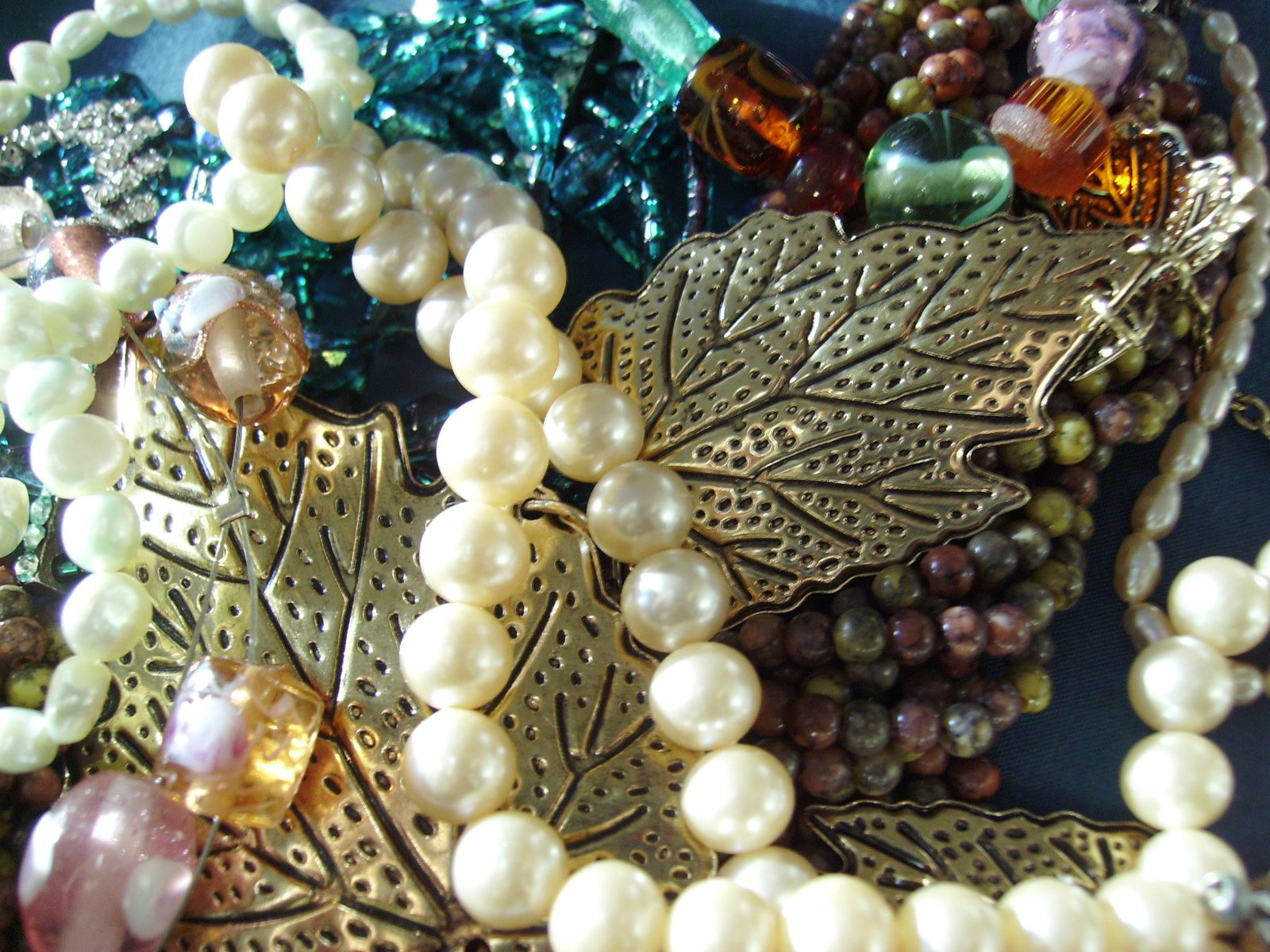 a close up of several beads, a leaf necklace and other decorative pieces