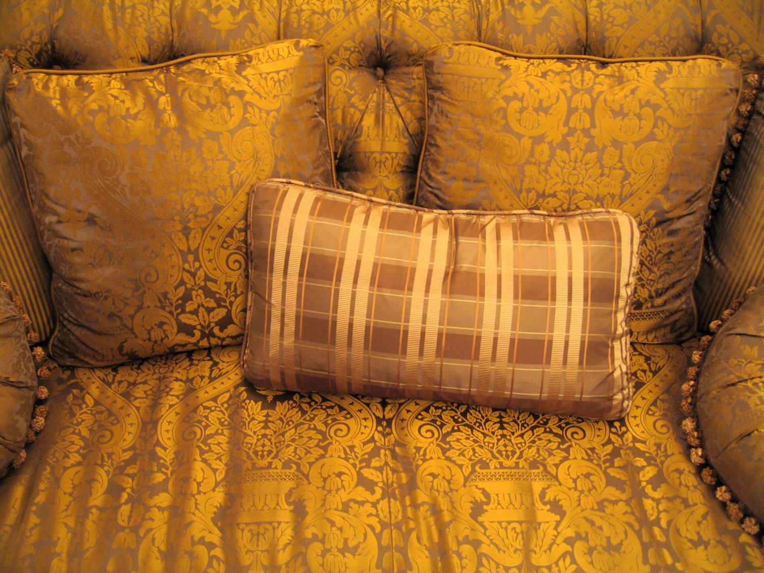 a gold couch with a plaid pillow and matching throw pillow