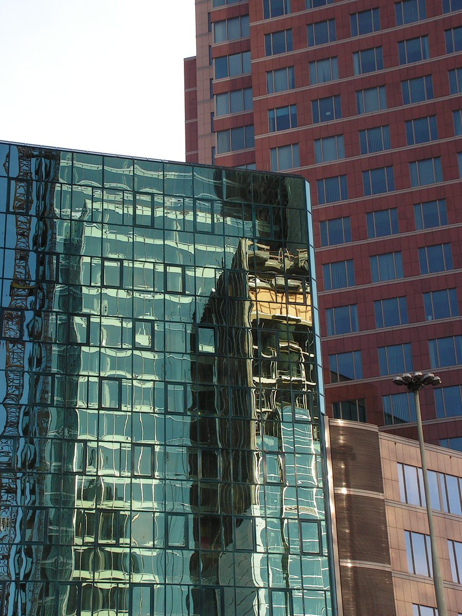 skyscrs behind a glass front building that features many windows