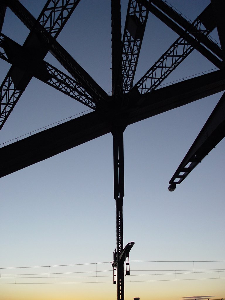 the sun is rising behind a train bridge