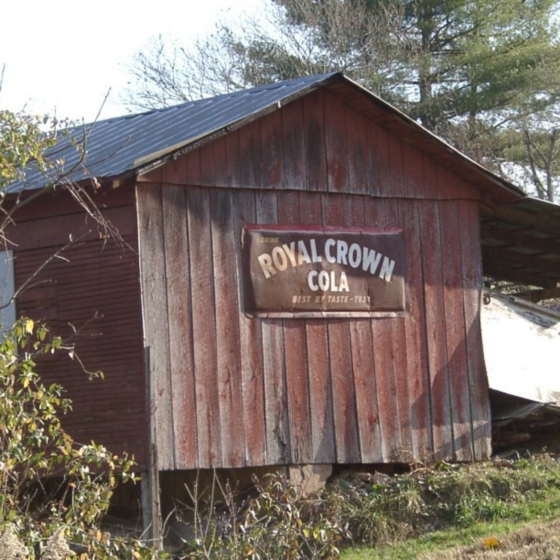 old farm building with metal sign sitting in the grass