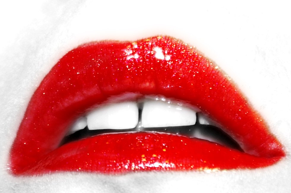 an open red lip with white teeth on a white surface