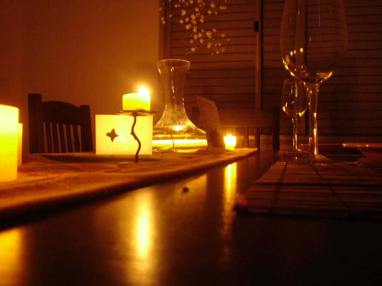 the interior of a dimly lit room with candles, furniture and window shutters