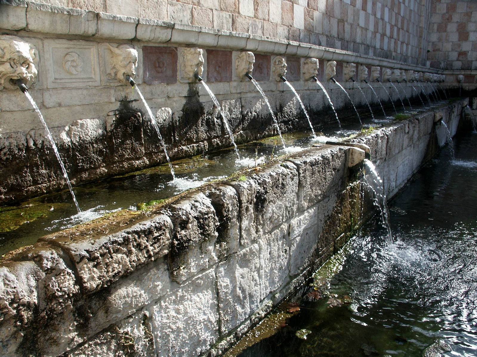 a row of fountain head on top of a wall