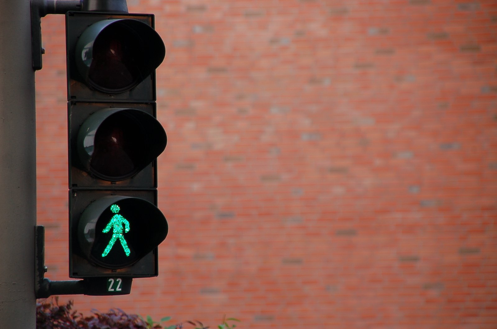 traffic light displaying green pedestrian signal and brick wall