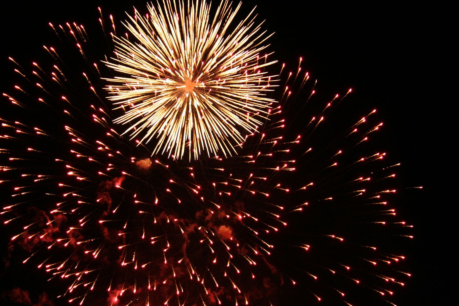 a night view of a huge firework with the top off and a building in the distance