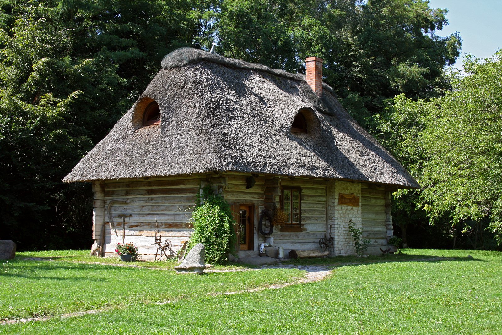 a cottage with a grass roof next to a field