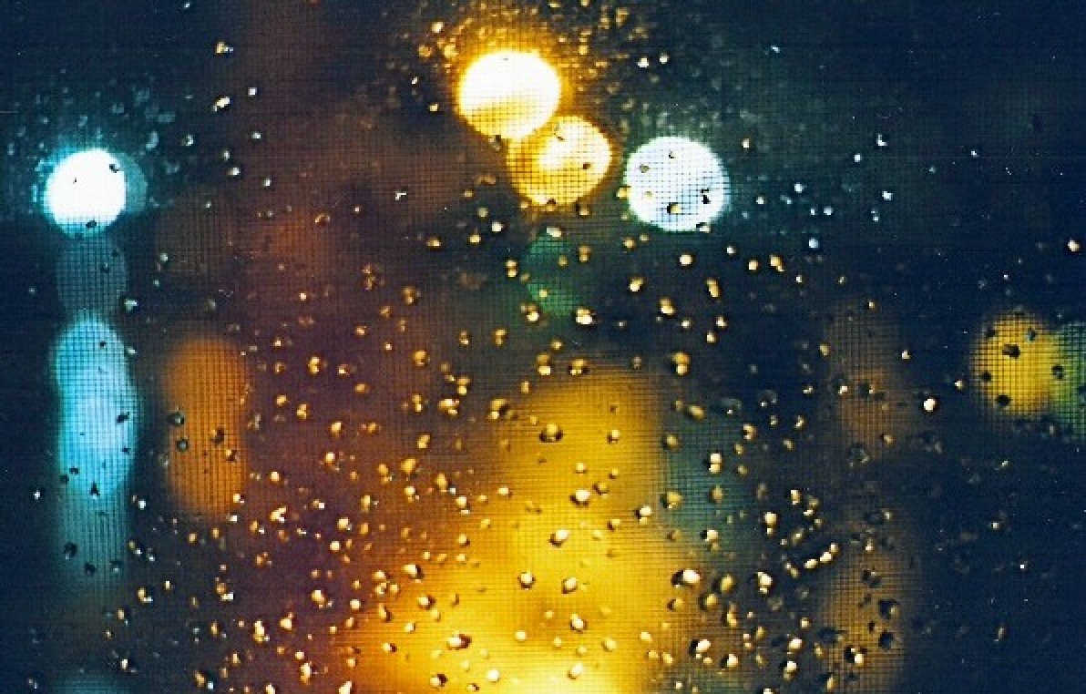 rain is on a window with blurred street lights