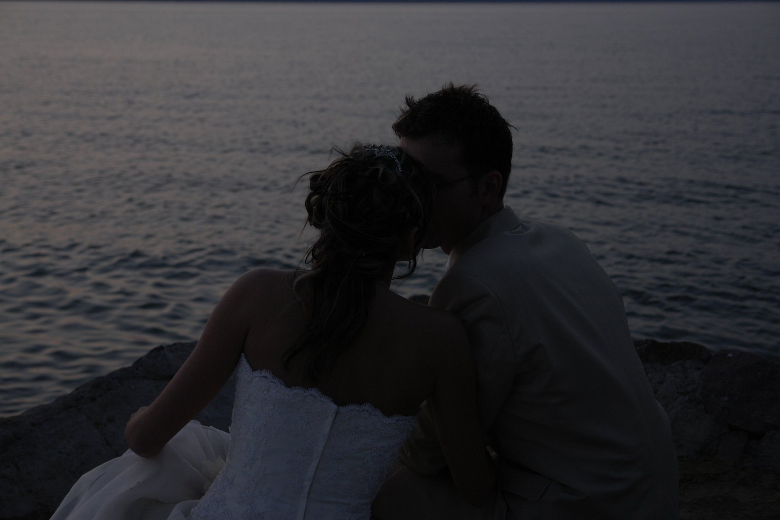 couple in formal dress sitting next to each other at a lake