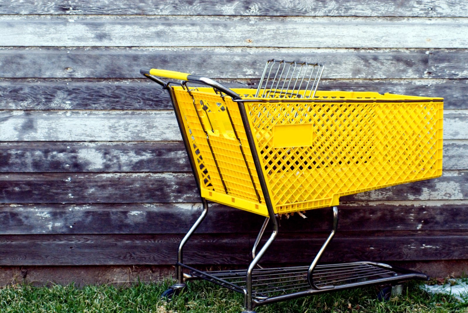 a yellow shopping cart is set up on the grass