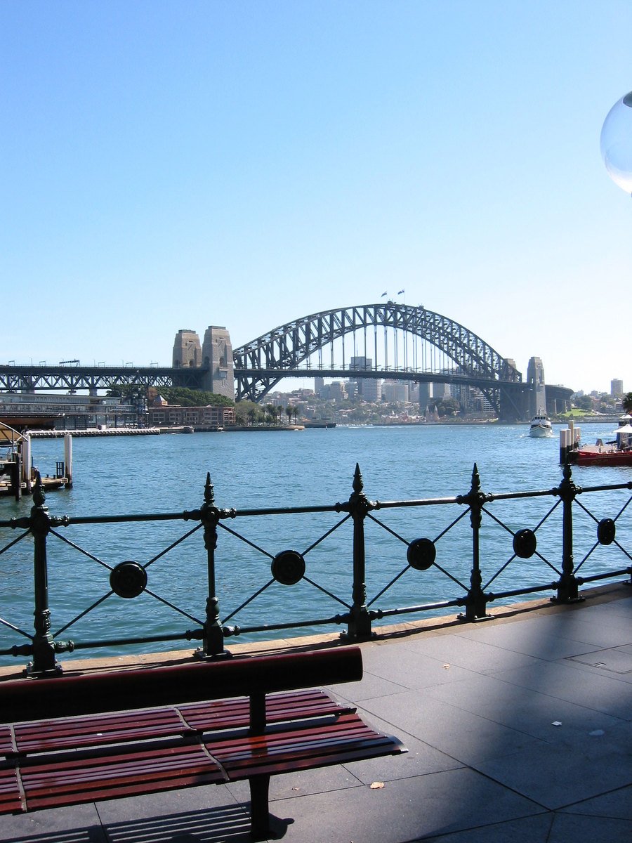 a wooden bench is overlooking the water and a bridge