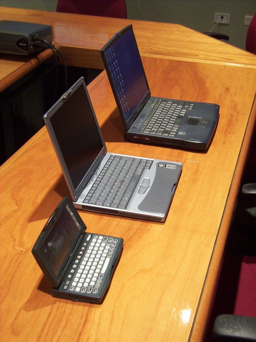 a wooden table with three laptop computers on it