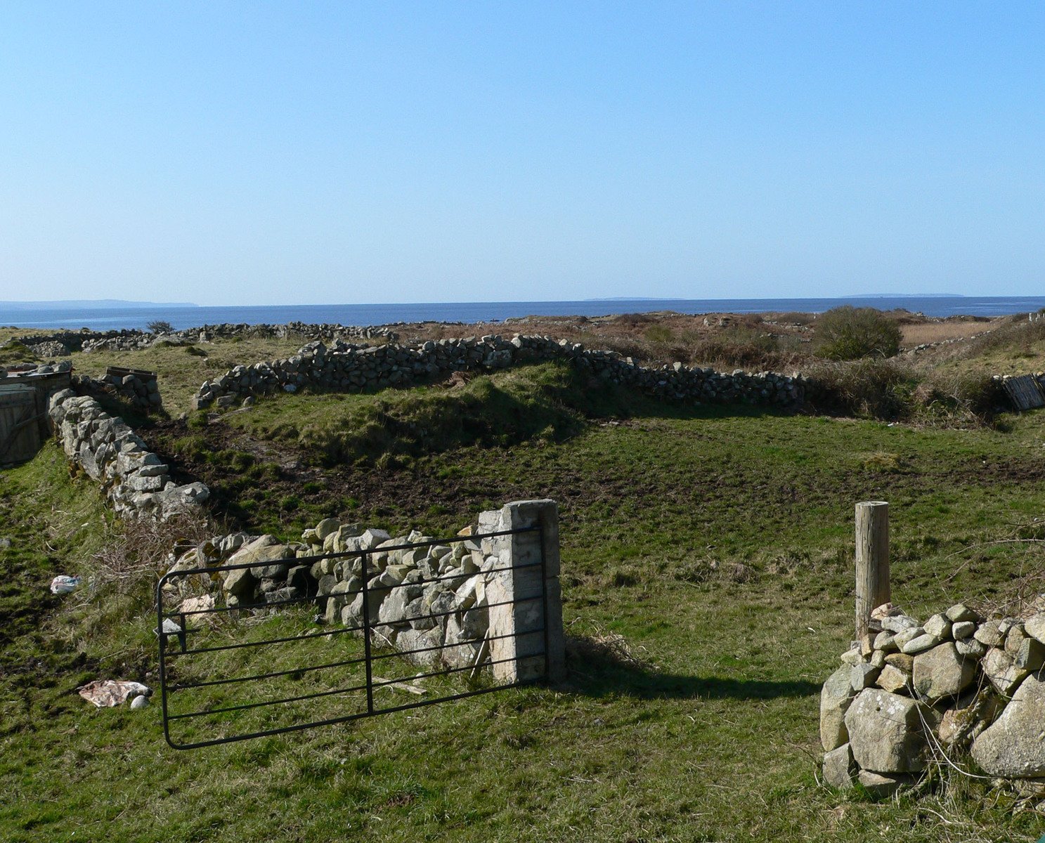 a stone wall is near the grassy field