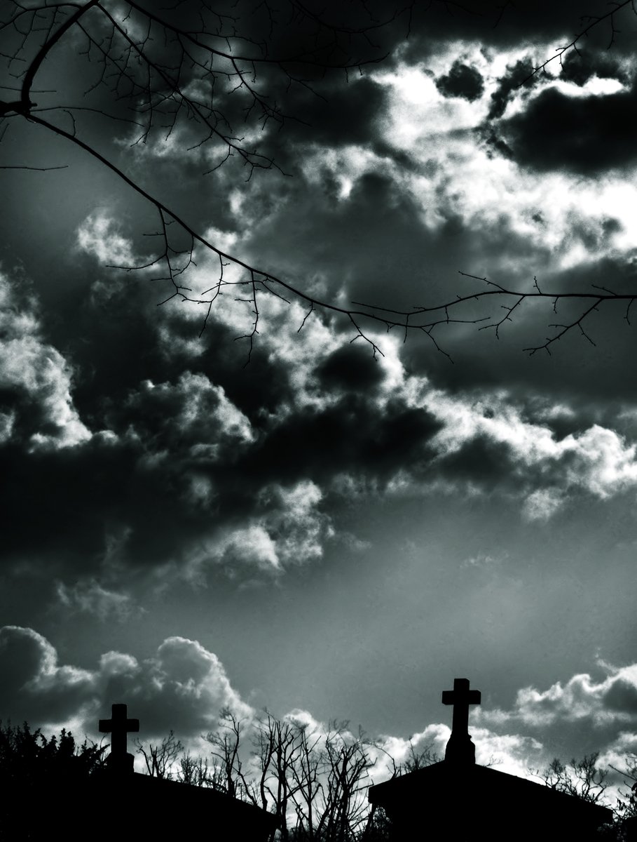 the silhouette of crosses and tree nches against a dark sky with clouds
